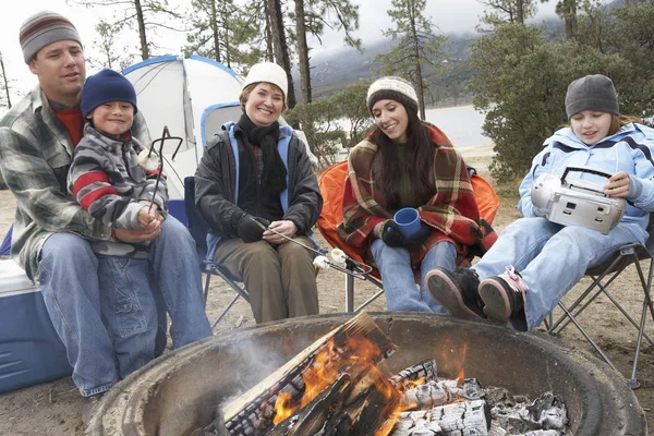 Happy family toasting marshmallow at campfire