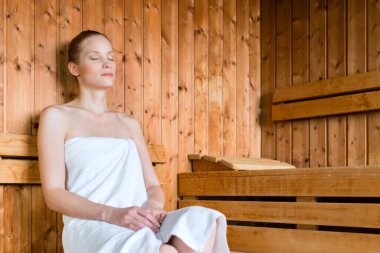 Young woman in wellness spa relaxing in wooden sauna clipart