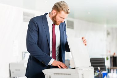 Businessman puts paper in the copying machine clipart