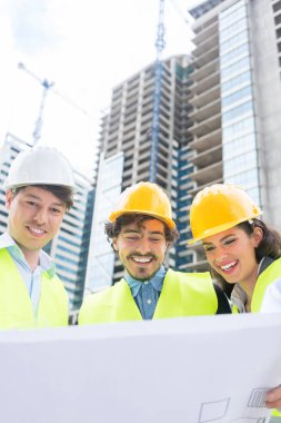 Architects and civil engineers with ground plot on construction site of highrise building clipart