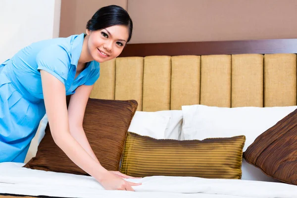 アジアのホテルの部屋でベッドを作って女中 — ストック写真
