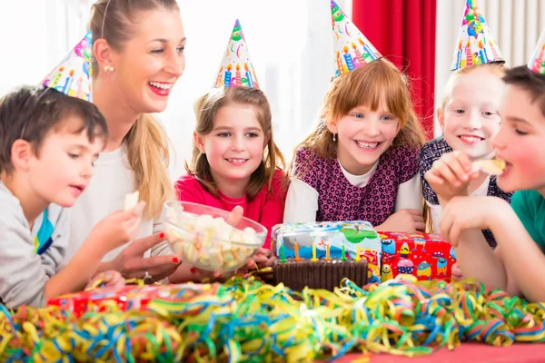 Dzieci Przyjęciu Urodzinowym Gryzące Cukierki Noszące Kapelusze Imprezowe — Zdjęcie stockowe