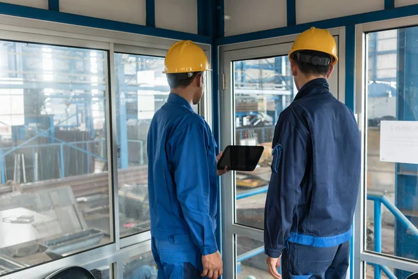 Vista Trasera Dos Trabajadores Que Usan Sombreros Duros Amarillos Mientras — Foto de Stock