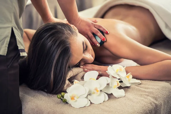 Young woman enjoying the therapeutic effects of a traditional hot stone massage at luxury spa and wellness center