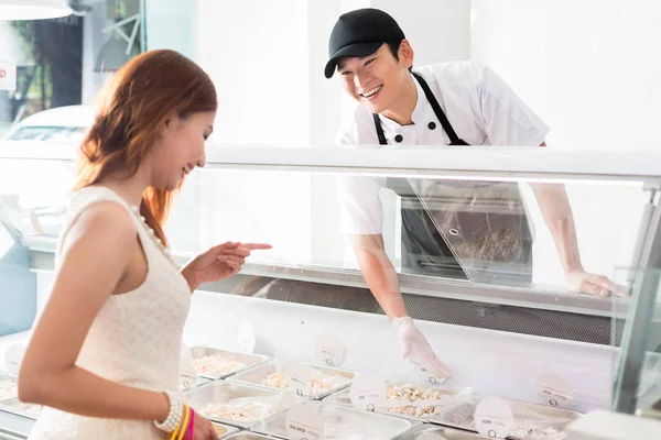 Usmívající Mladý Asijský Pracovník Pomáhá Zákazníkovi Lahůdkářství Když Vybírá Jídlo — Stock fotografie