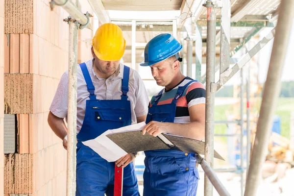 Two Construction Workers Site Helmets Having Discussion Scaffold Plans Blueprints — Stock Photo, Image