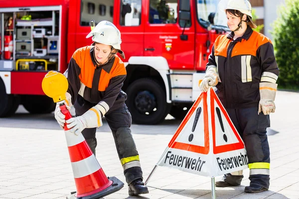 Female fire fighters in emergency operation setting up attention sign