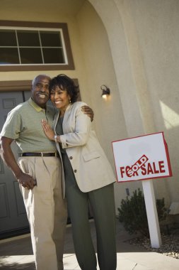 Middle-aged couple in front of new home clipart