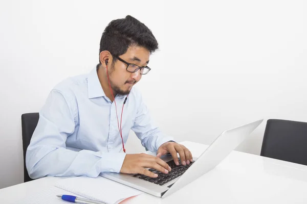 Young businessman listening music while using laptop in office