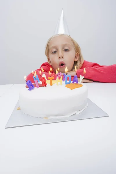 女の子吹くキャンドルオン誕生日ケーキ上のテーブルで家 — ストック写真