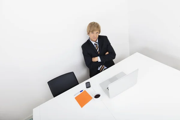 带着笔记本电脑坐在办公桌前的自信商人的画像 — 图库照片