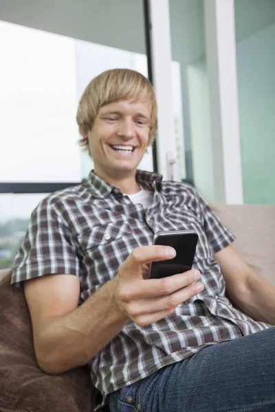 Fröhlicher Mittlerer Erwachsener Mann Textet Auf Sofa Hause — Stockfoto