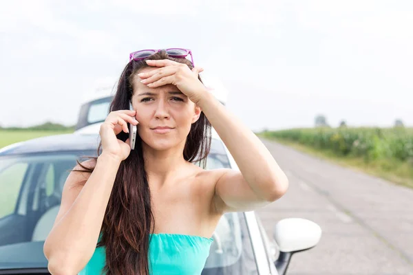 使用手机对辆抛锚的汽车在道路上的紧张女人的画像 — 图库照片
