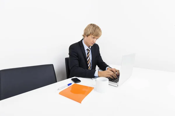 商人在办公室的桌子上的笔记本电脑上工作 免版税图库照片