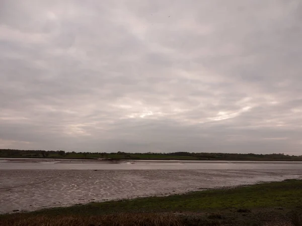 Low tide summer sky nightfall grey clouds mood and reds with river running through in wivenhoe essex uk england