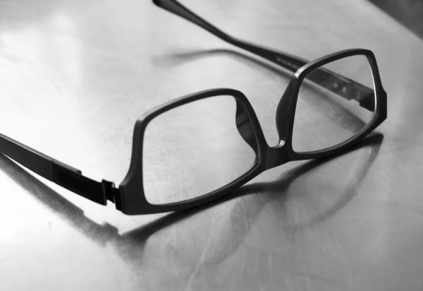 Schwarz Weißes Foto Von Kunststoffbrillen Auf Stahltisch — Stockfoto