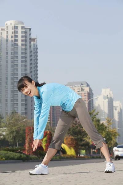 Chinese woman stretching in city before exercise