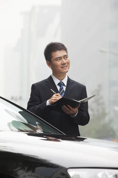 Chinese businessman writing in notebook