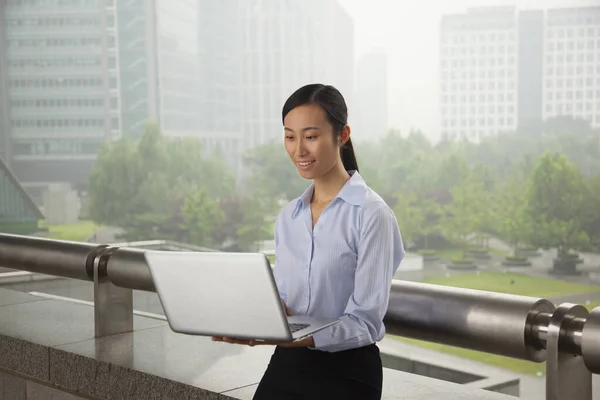 Chinese businesswoman using laptop outdoors