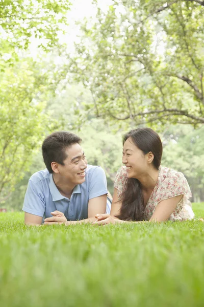 Chinese couple laying in grass in park