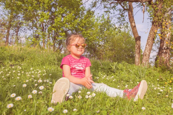 春意盎然的小女孩 戴着太阳镜 躺在绿茵的草地上 过着自然的生活 — 图库照片