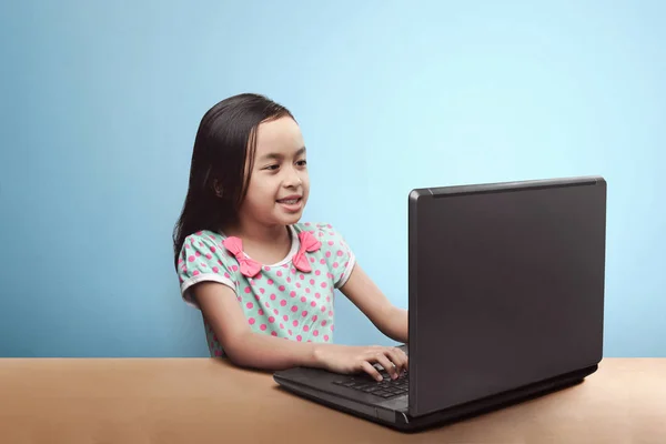 Uśmiechnięte Azjatyckie Dziecko Laptopem Stole Niebieskim Tle — Zdjęcie stockowe