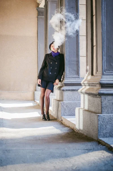 禁煙電子タバコ煙蒸気を吹く黒いコート スカート 黒の帽子に 白い毛で若い美しい女性の肖像画 — ストック写真