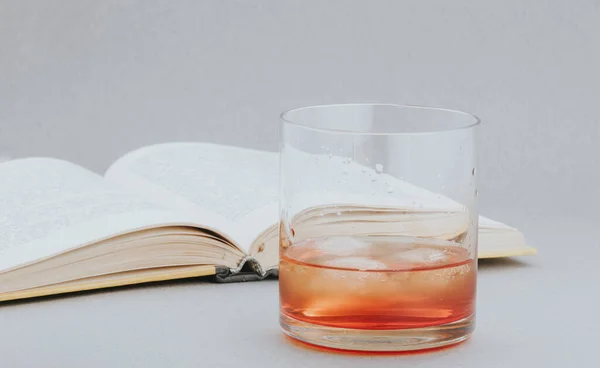 Ένα Ποτήρι Ιρλανδικό Ουίσκι Παγάκια Δίπλα Ένα Ανοιχτό Βιβλίο Γκρι — Φωτογραφία Αρχείου
