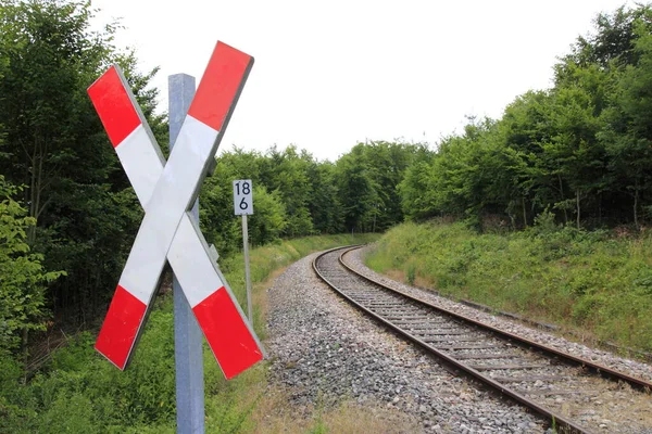 st. andrew\'s cross at a railroad crossing with a view of the tracks,which disappear in a right turn.