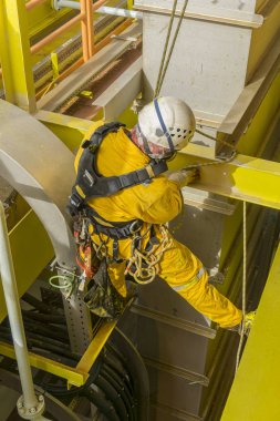 Working at height. A commercial abseiler with respiratory protection and fall arrestor device doing painting inspection on oil and gas platform. clipart