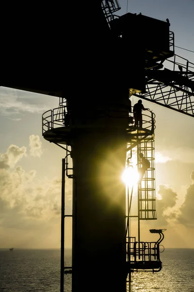 Oil and gas industries. Silhouette of pedestal crane operator working on oil and gas platform in the middle of the sea desending using monkey ladder after working hours.
