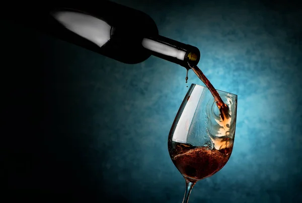 青い背景にワイングラスに注ぐワイン — ストック写真