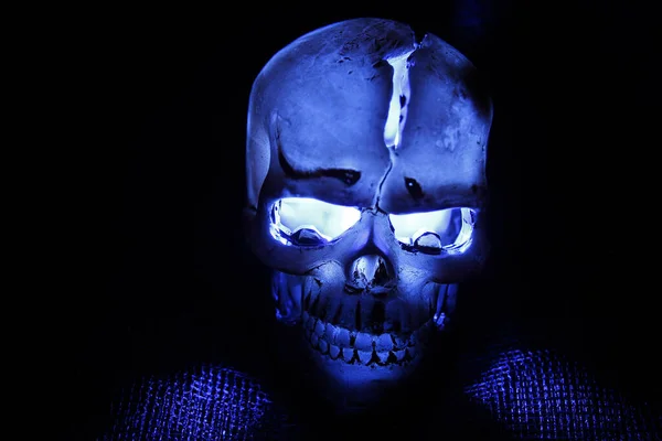 黑暗中带有蓝光眼窝的塑料颅骨 — 图库照片