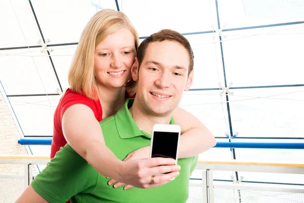 白い背景の若いカップルが携帯電話で自画像を撮る — ストック写真