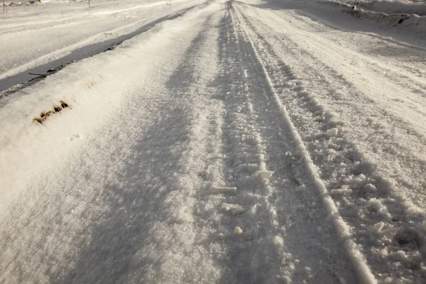 雪の道路の一部を閉じるまでの大まかなカバー 車の車輪の痕跡がある — ストック写真