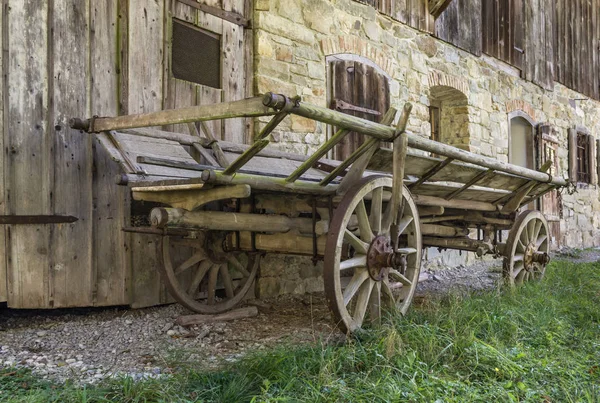 Historic horse driven cart in front of an old farmhouse. Wooden wheels.