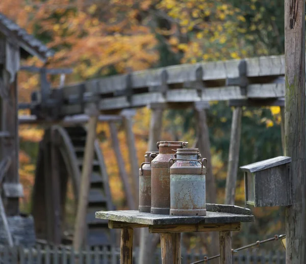 Drei Alte Milchkannen Auf Einem Tisch Wassermühle Mit Sichtbarem Wasserrad — Stockfoto