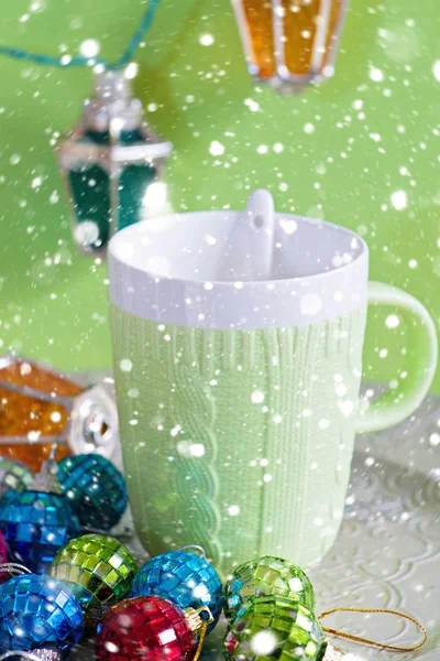 Tasse Und Weihnachtsspielzeug Auf Grünem Hintergrund Über Schnee — Stockfoto