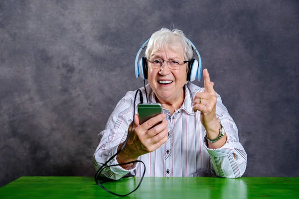 gray hairy elderly woman listening music with headphone
