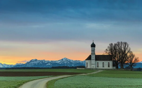 Yeşil Tarlada Eski Bir Kilisenin Üzerinde Gün Doğarken Alp Dağları — Stok fotoğraf