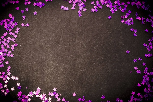 Purple glitter stars on a black background with copy space