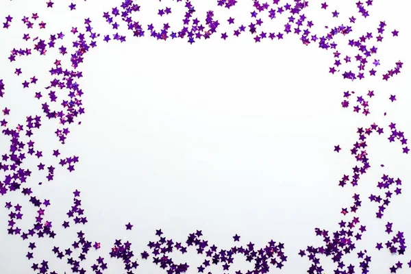 Purple glitter stars on a white background with copy space
