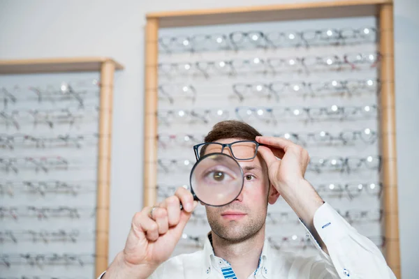 Optician Shop Young Man Magnifier Selecting New Reading Glasses — Stock Photo, Image