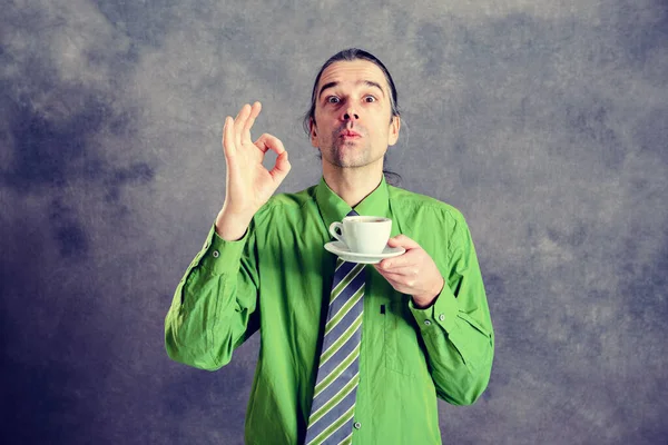 Yeşil Gömlekli Kravatlı Genç Adam Gri Arka Planda Kahve Içiyor — Stok fotoğraf