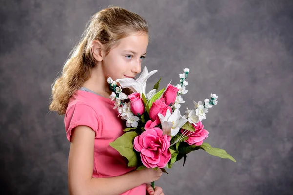 グレーの背景の前で素敵なブロンドの女の子の花束 — ストック写真