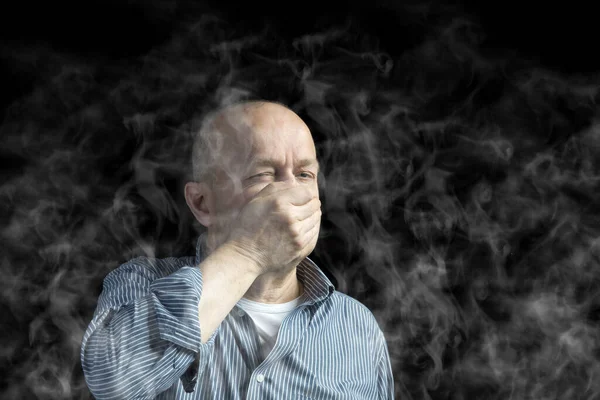 男は煙から身を守るために口を覆い — ストック写真