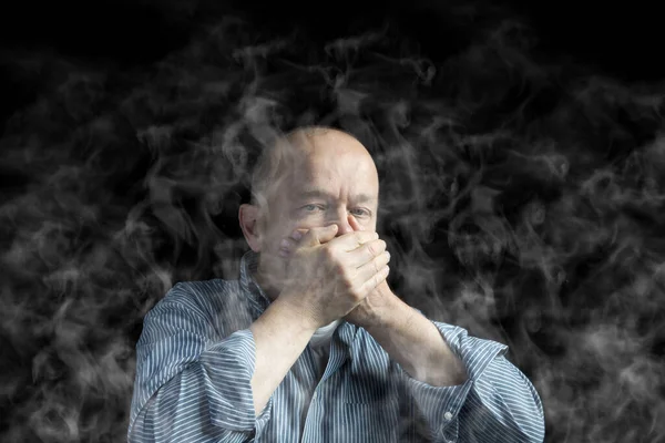 a man covers his mouth to protect himself from smoke