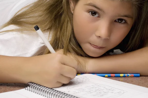 Portrait of a schoolgirl writing on a textbook with a pencil