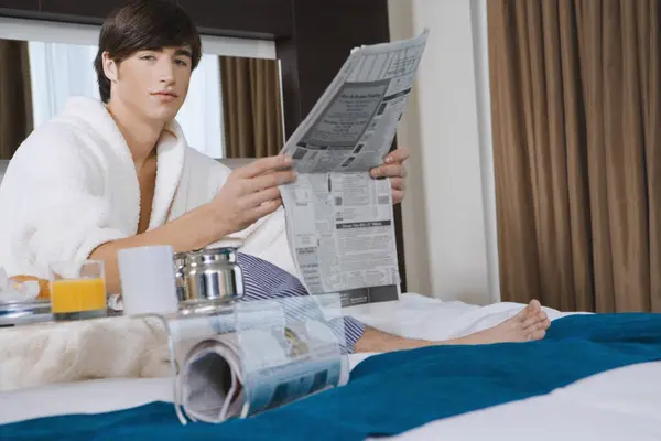 Portrait of a young man holding a newspaper