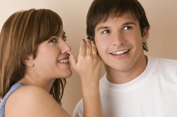 Young woman whispering to a young man